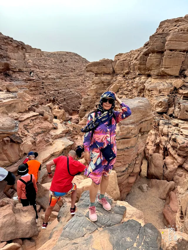 媽媽張開手站在峽谷高處，腳下仍是需要小心落腳的岩面