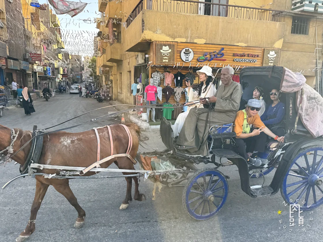 馬車穿過盧克索街區時,商店、行人與其他馬車都從身邊擦過