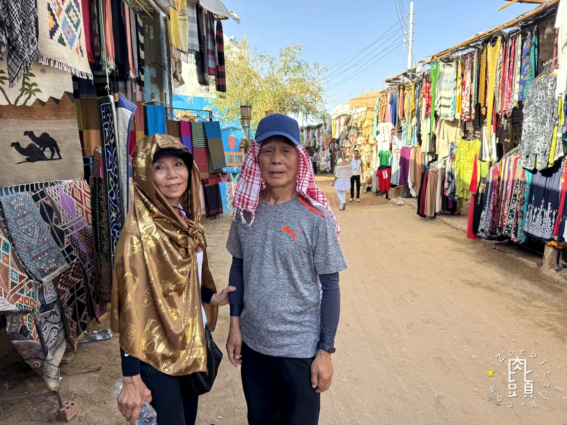 努比亞村的街道兩旁掛滿布料與手工品，我們在人群間慢慢往裡走