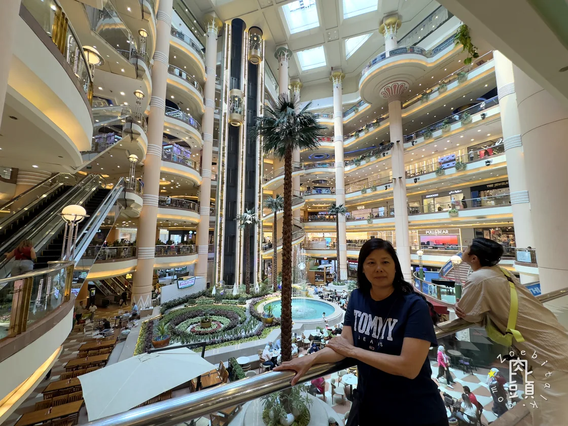 百貨中庭的樓層一圈圈往上延伸,媽媽停在欄杆旁先看完整空間